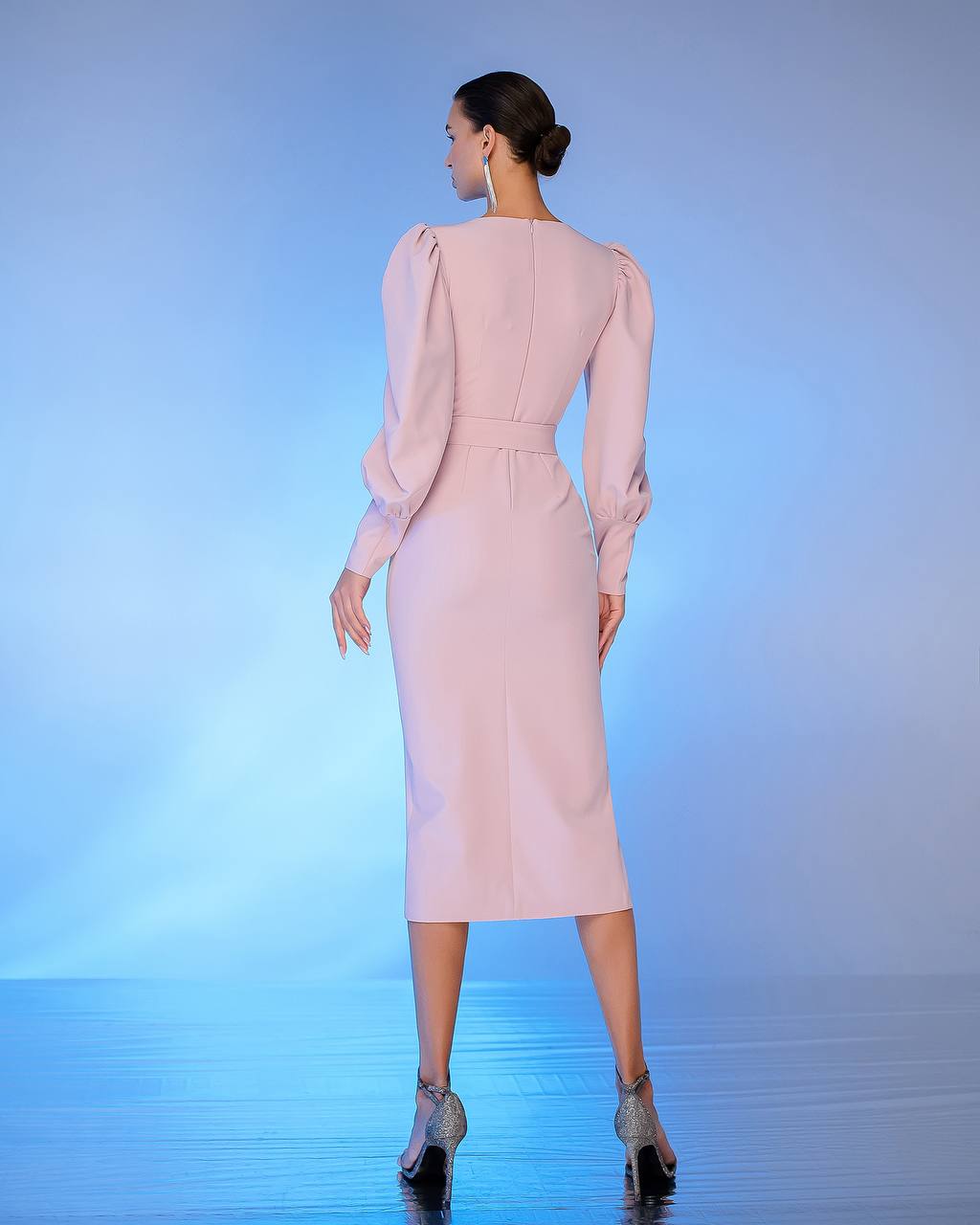 Woman wearing a light pink dress with long sleeves on a gradient blue background