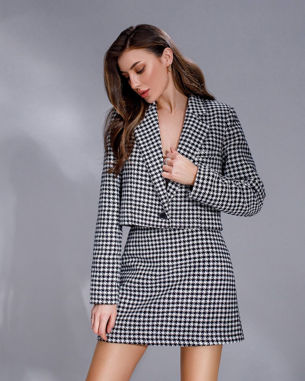 Woman wearing a black and white checkered suit against a gray background