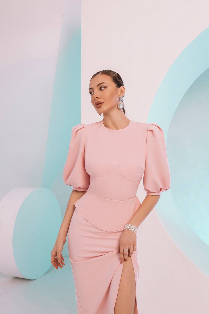 Woman wearing a pink dress with puffed sleeves against a pastel-colored background