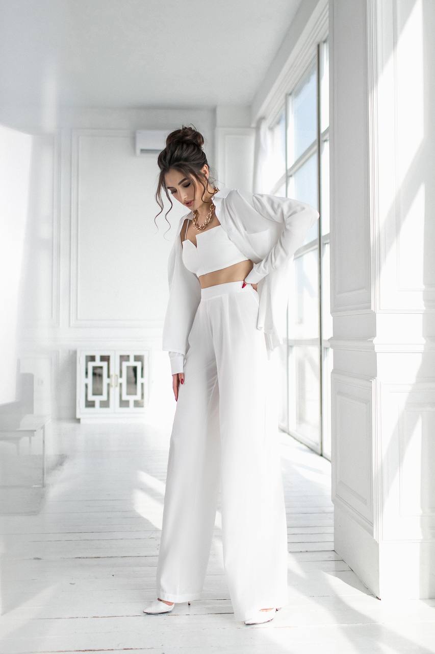 Woman in a white outfit standing in a bright, minimalistic room.