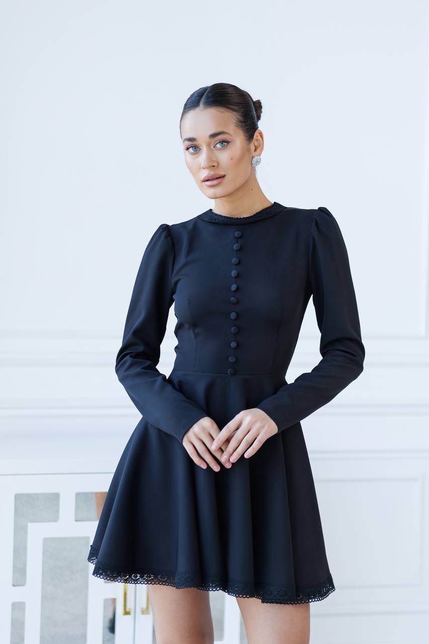 Woman wearing a black dress with long sleeves against a white background