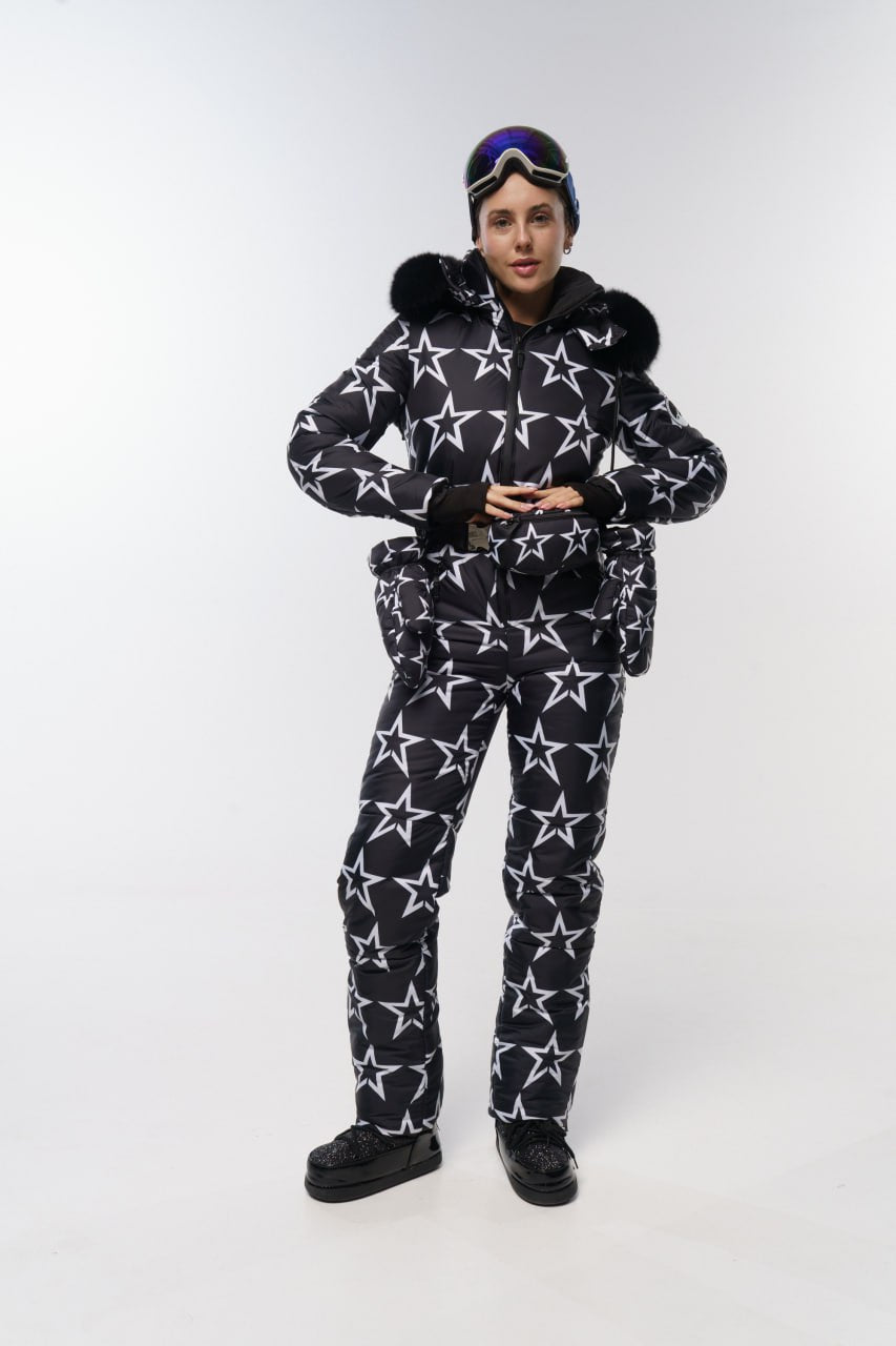 Person wearing a black and white star-patterned snowsuit on a white background