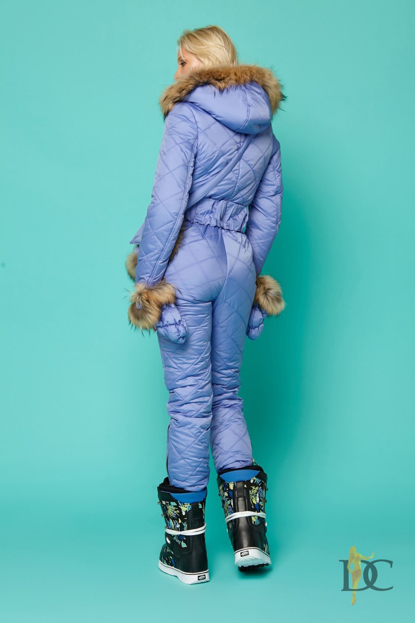 Person wearing a blue winter suit with fur trim on a teal background