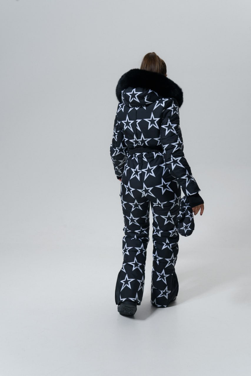 Person wearing a star-patterned snowsuit with a fur-lined hood on a white background