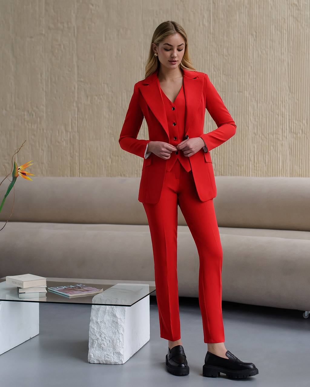 Woman wearing a red suit standing in a modern living room.