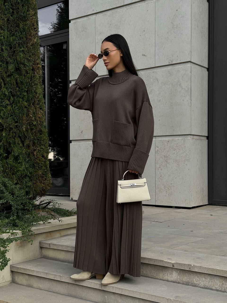Woman in a brown outfit standing on steps outside a building
