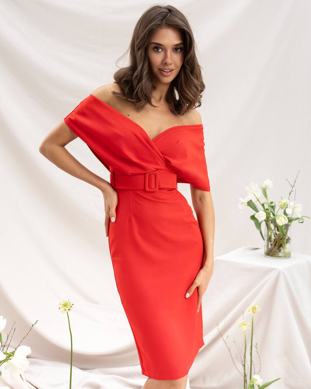 Woman wearing a red off-shoulder dress against a white background