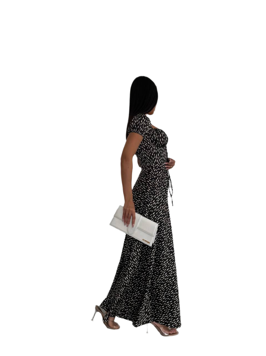 Woman in a black and white patterned dress holding a clutch on a white background