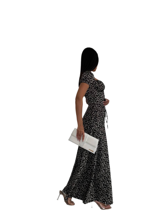 Woman in a black and white patterned dress holding a clutch on a white background