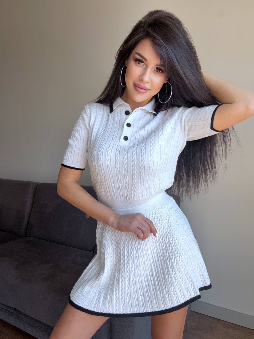 Woman wearing a white dress with black trim in an indoor setting