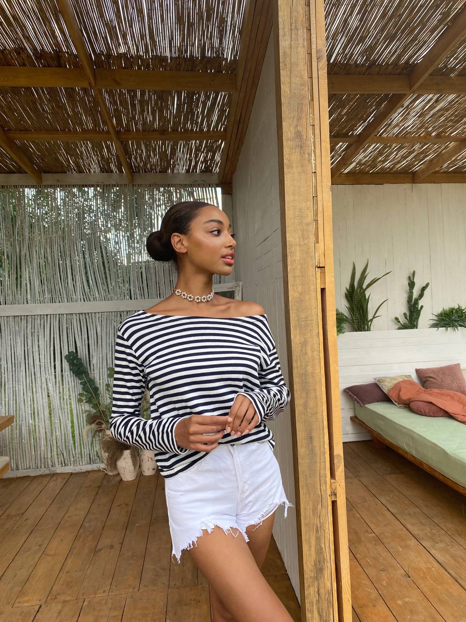 Woman wearing a black and white striped top and white shorts in a tropical setting.