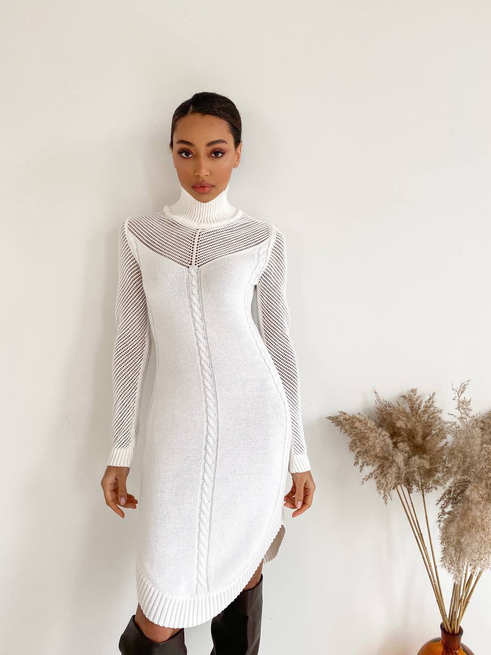 Woman wearing a white dress with black pattern against a plain background