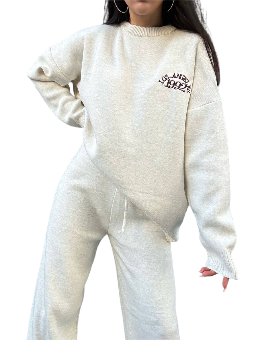 Person wearing a white sweater with text and matching pants on a white background