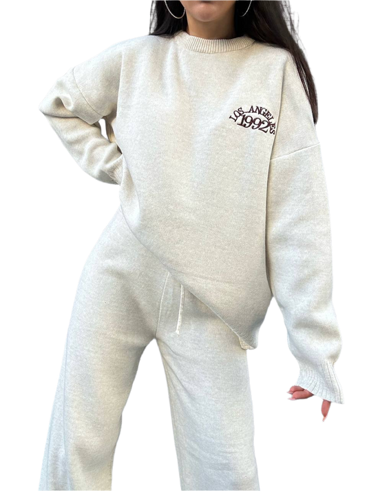 Person wearing a white sweater with text and matching pants on a white background