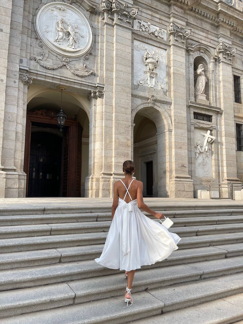 Woman in a white dress standing on steps in front of an ornate building