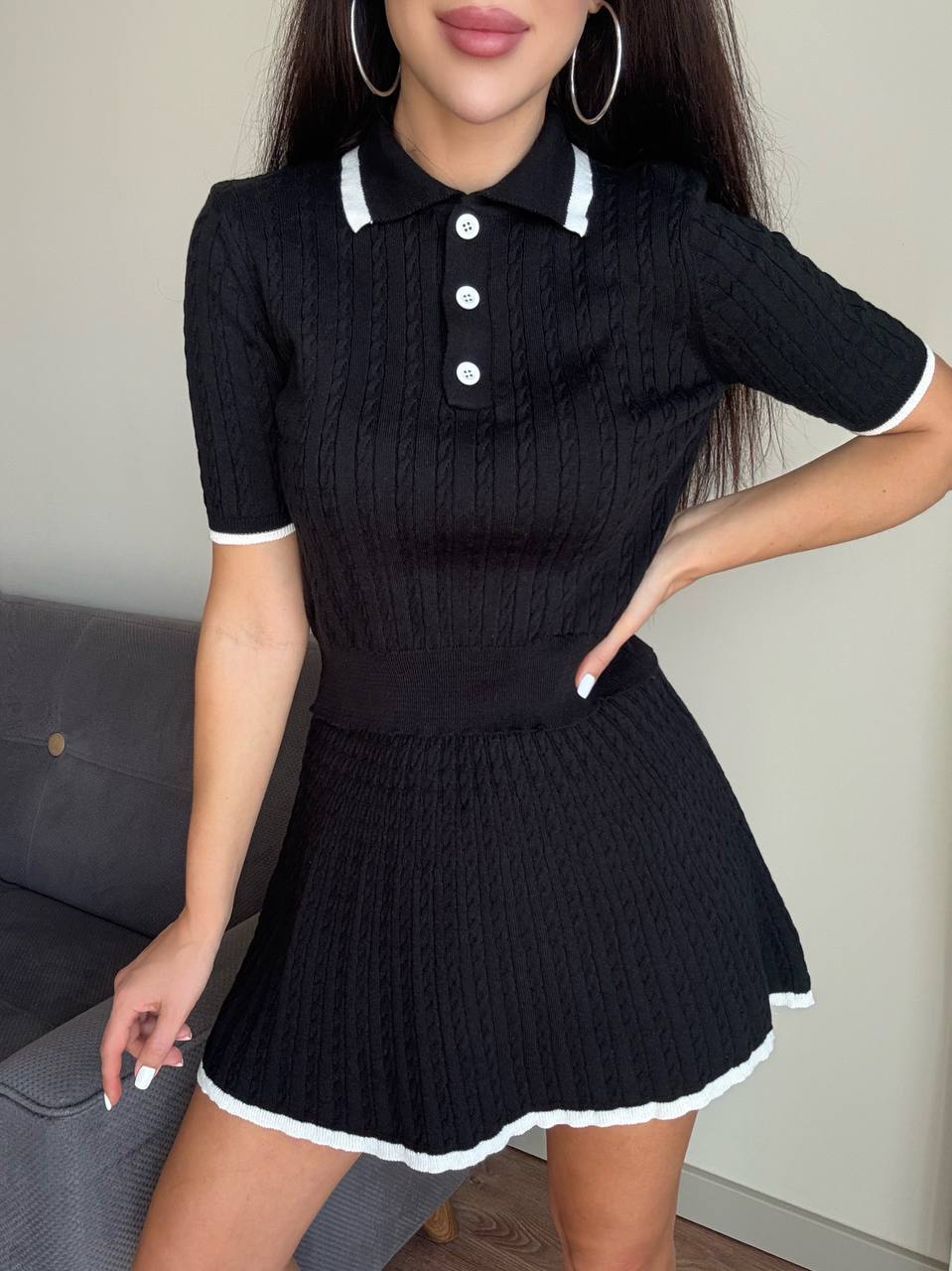 Woman wearing a black ribbed dress with white trim in an indoor setting.