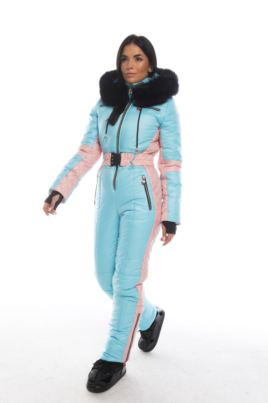 Person wearing a light blue and pink snowsuit with black fur trim on a white background