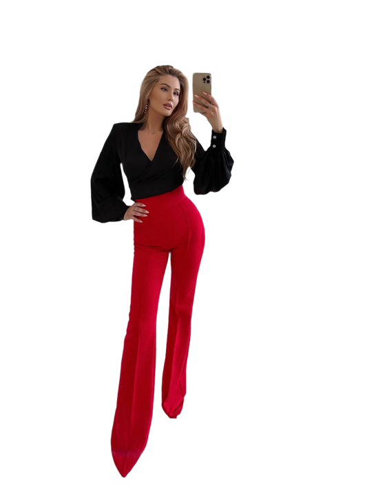 Woman taking a selfie wearing a black blazer and red pants on a white background
