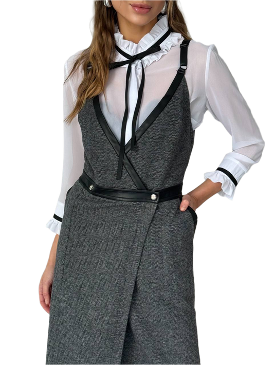 Woman wearing a gray vest over a white blouse with black accents on a white background