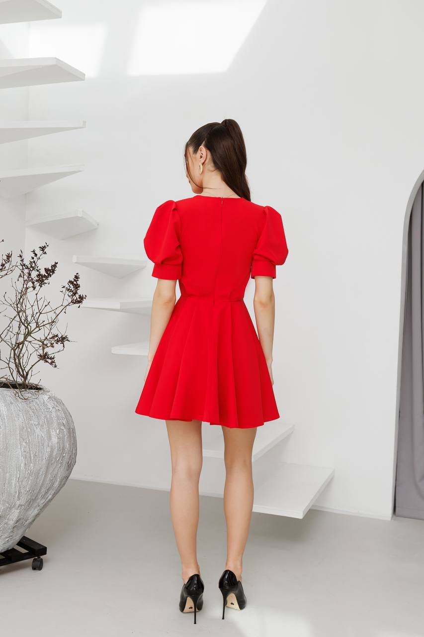 Woman wearing a red dress standing in a modern indoor setting.