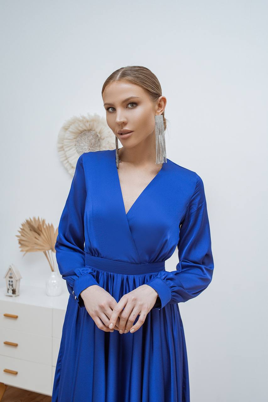 Woman wearing a blue dress with long earrings against a white background