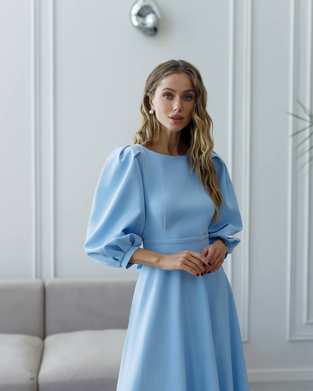 Woman wearing a light blue dress with puffed sleeves in an indoor setting.