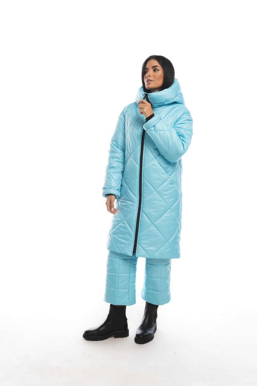 Person wearing a light blue quilted coat on a white background