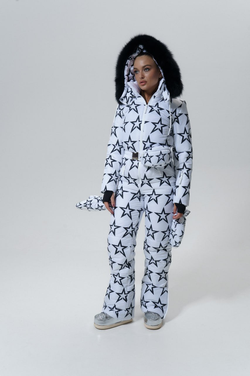 Person wearing a white snowsuit with black star patterns on a plain background