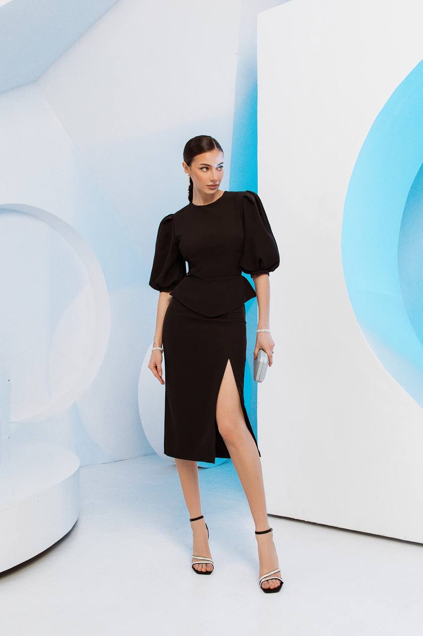Woman in a black dress standing in a futuristic, light blue and white interior.