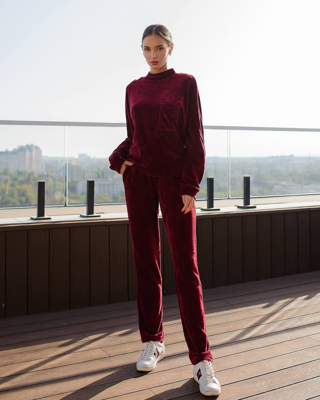 Person wearing a burgundy velvet outfit on a rooftop with a cityscape background