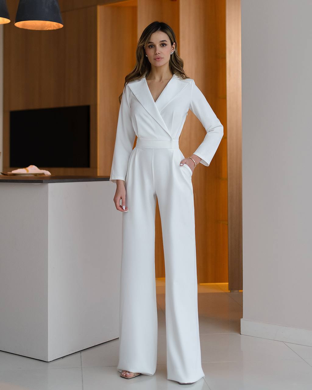 Woman wearing a white jumpsuit in an indoor setting