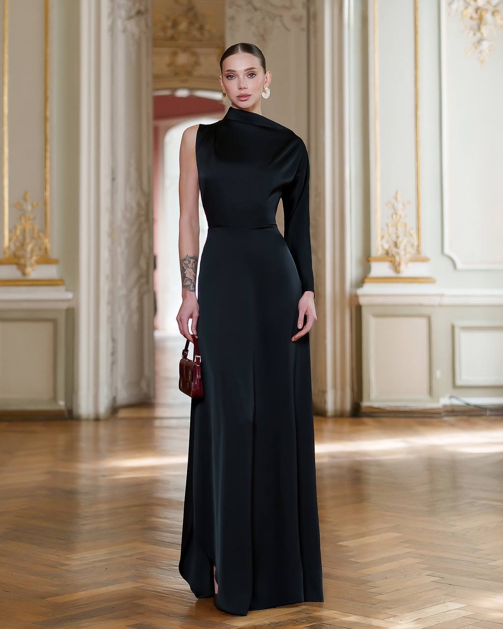 Woman in a black evening gown standing in an elegant interior setting