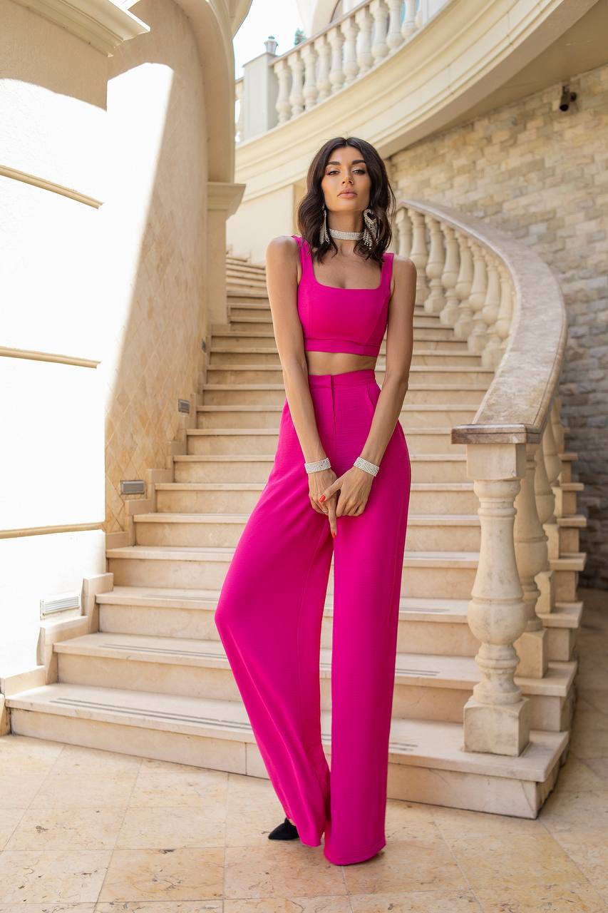 Woman in a bright pink outfit standing on a stone staircase.