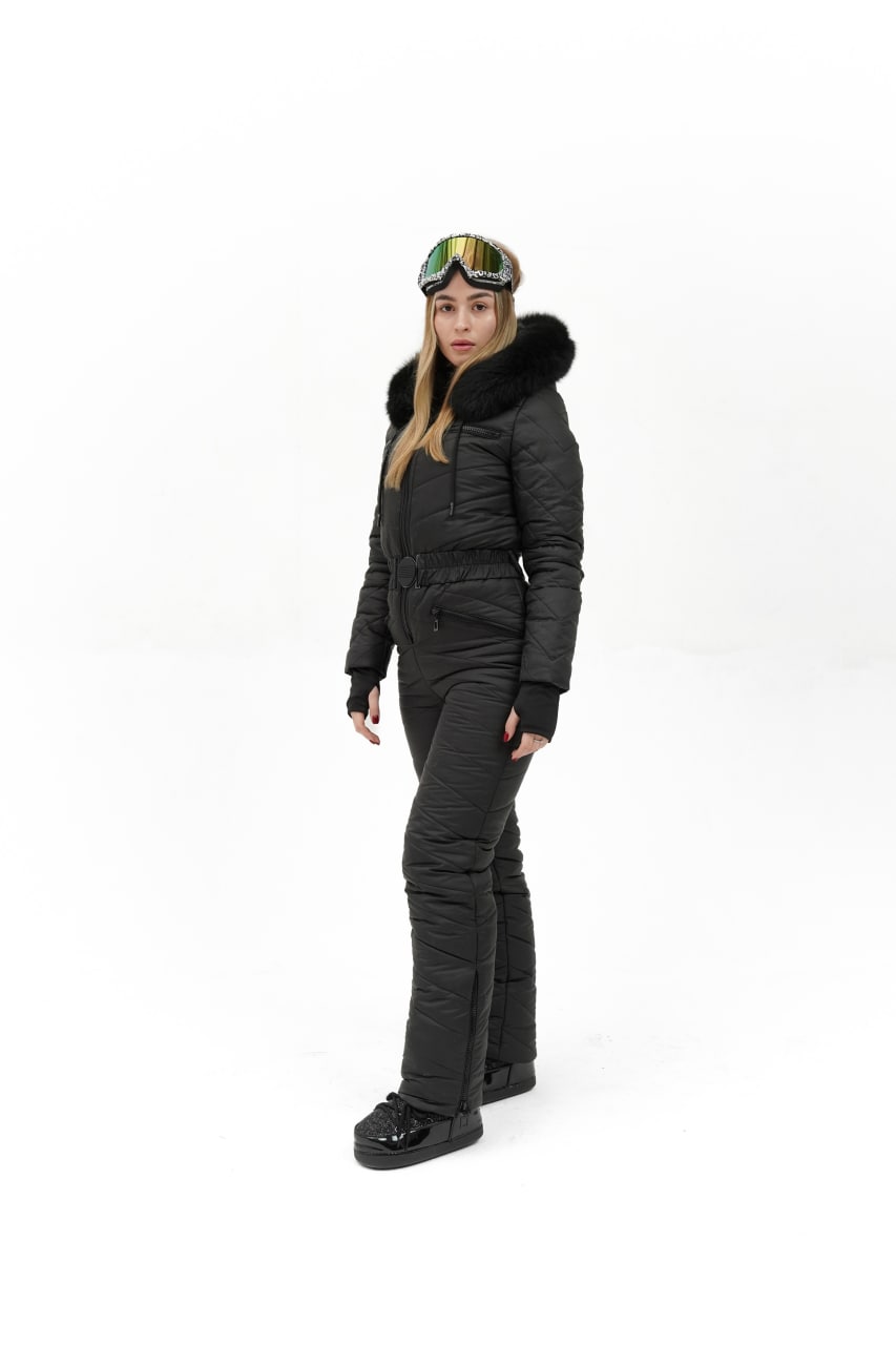 Person wearing a black snowsuit with goggles on a white background