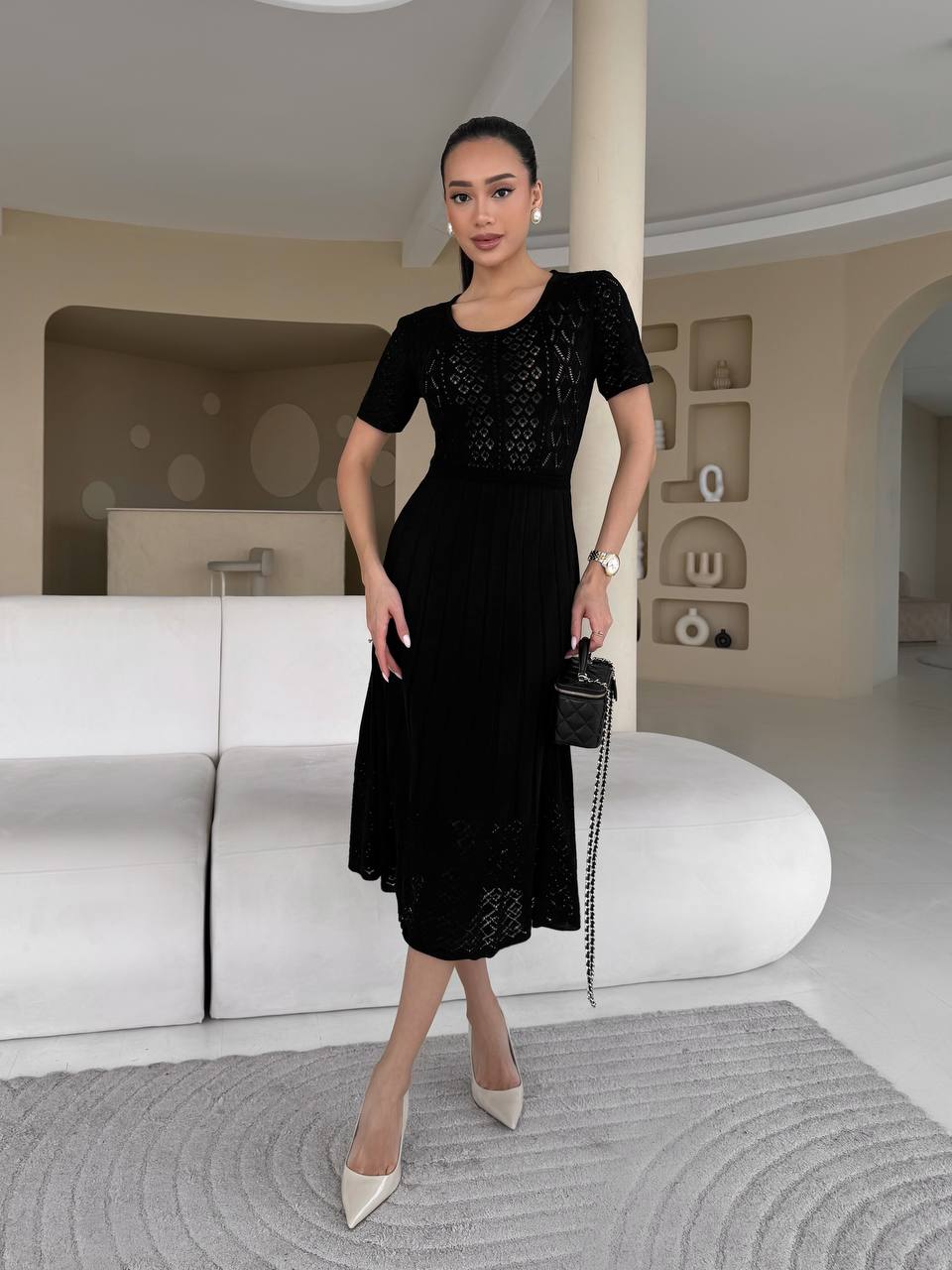 Woman in a black dress standing in a modern interior setting