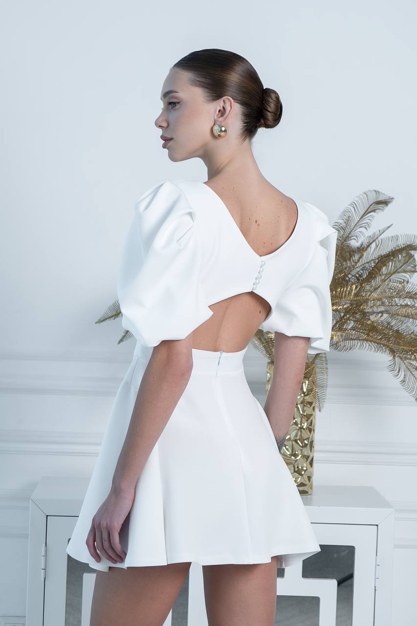 Woman wearing a white dress with cut-out design in a minimalistic setting