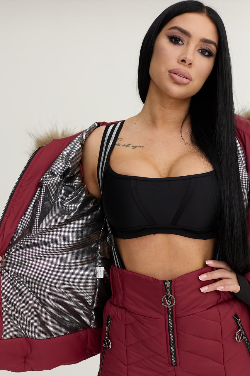 Woman wearing a black sports bra and red puffer jacket with a gray interior.