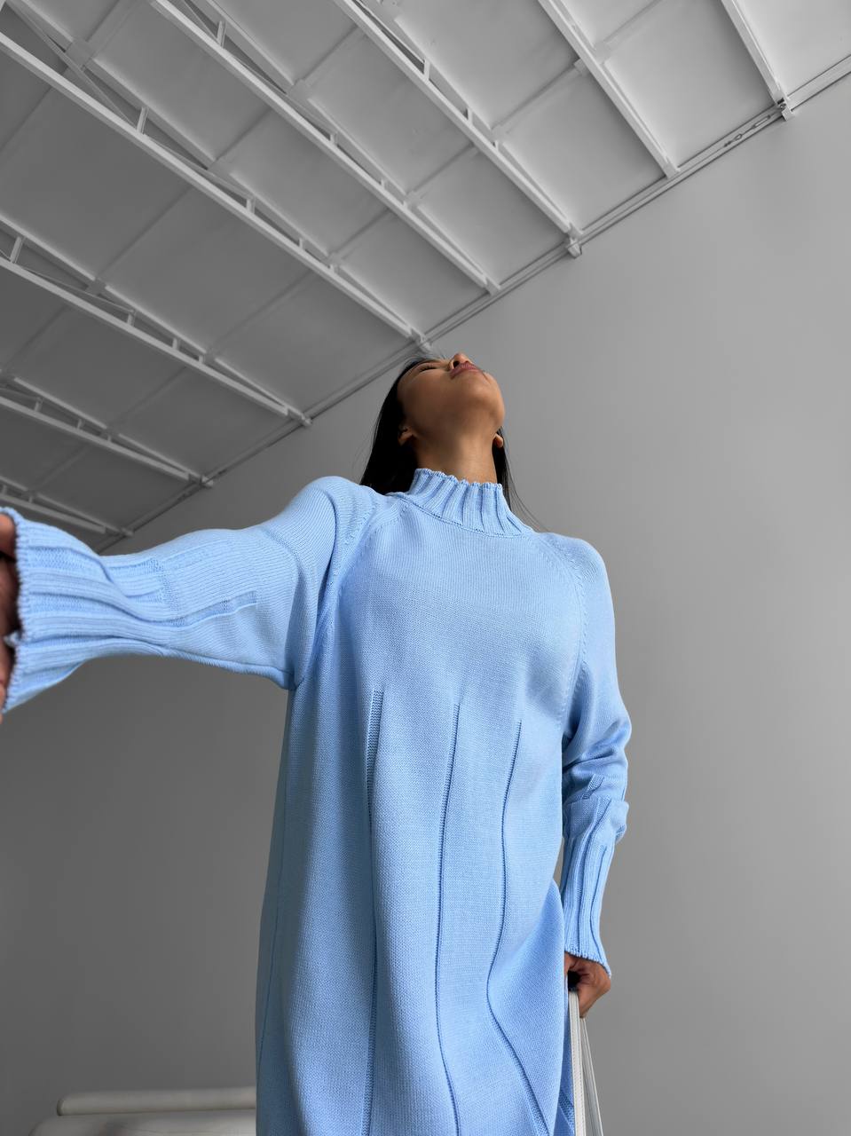 Person wearing a light blue sweater standing against a plain background
