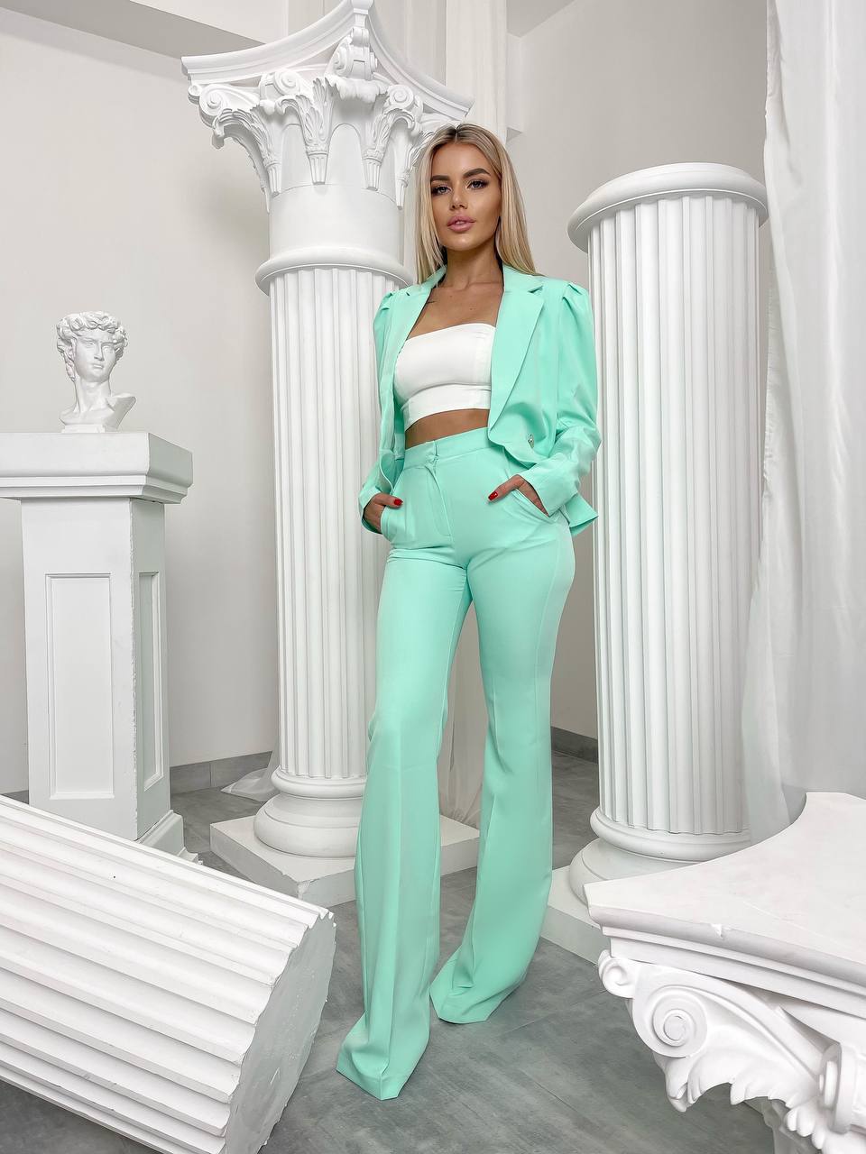 Woman in a mint green suit standing in a white classical setting