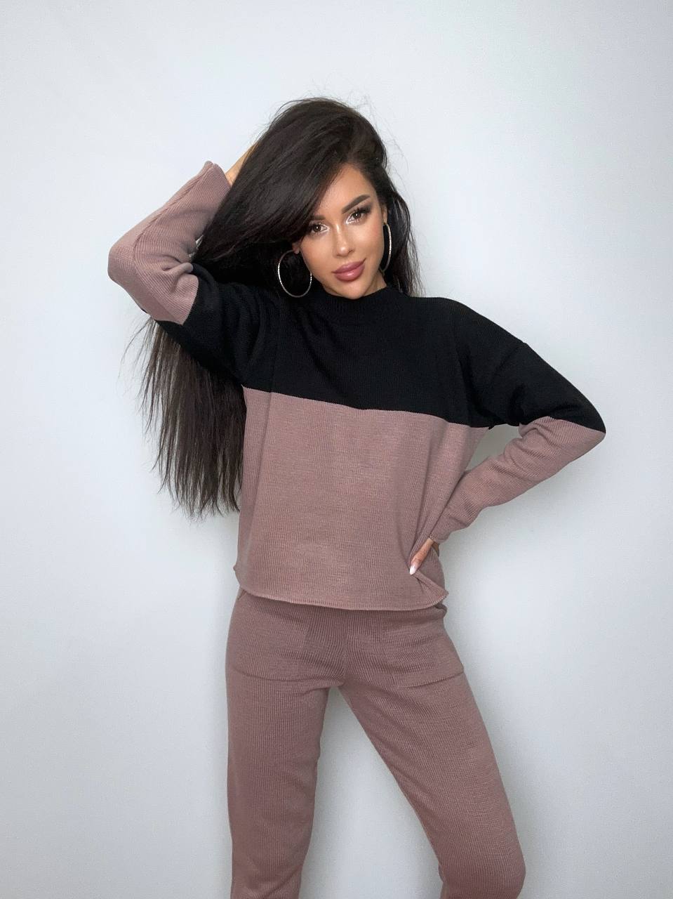 Woman wearing a two-tone brown and black outfit against a white background