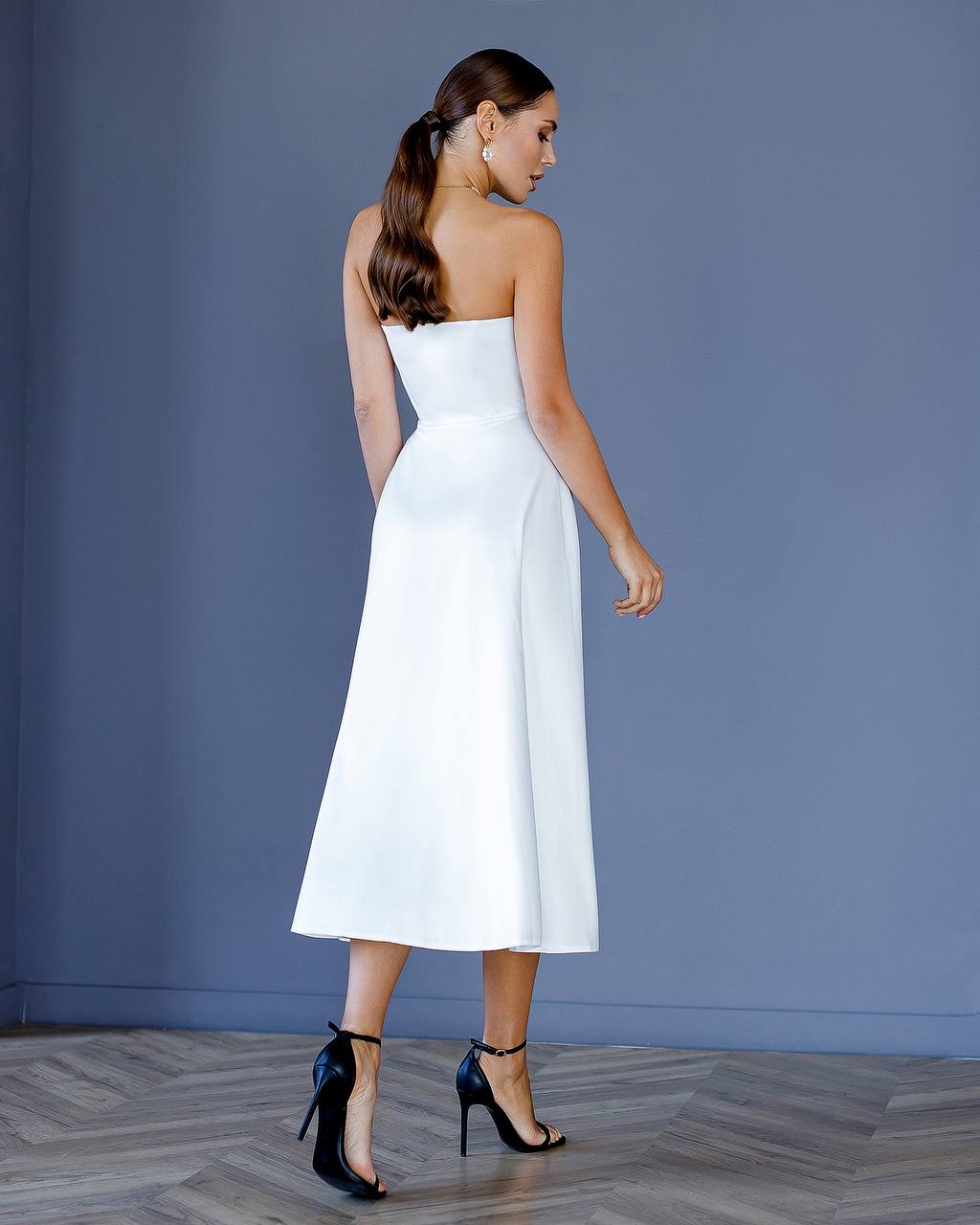 Woman wearing a white strapless dress against a gray background