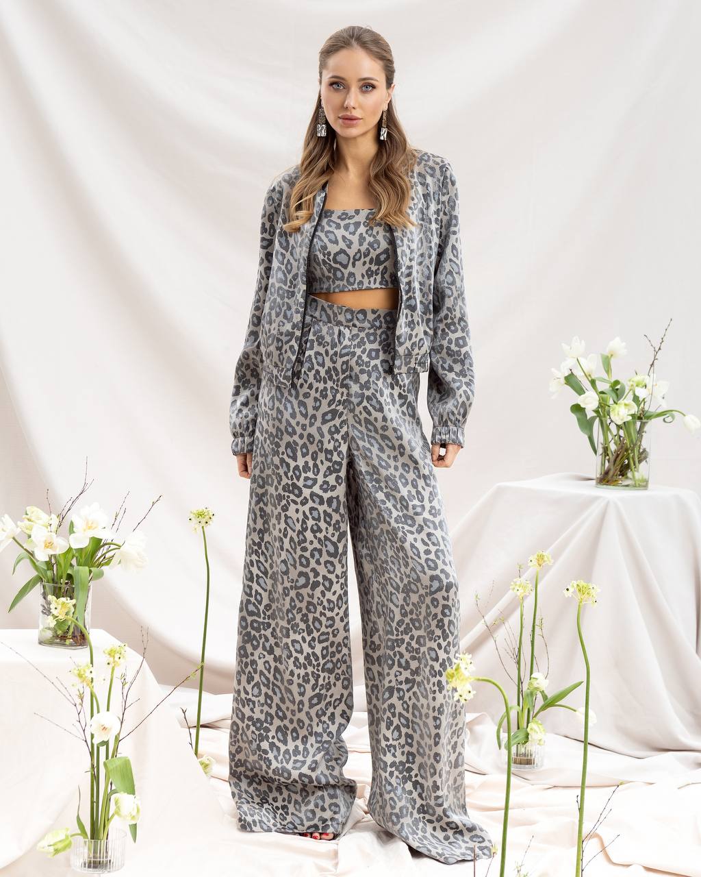 Woman wearing a leopard print outfit with a white background and flowers.