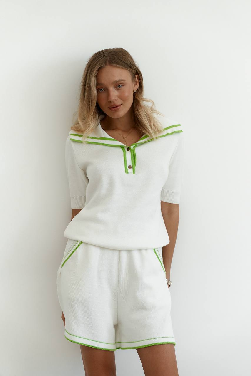 Woman wearing a white outfit with green accents against a white background