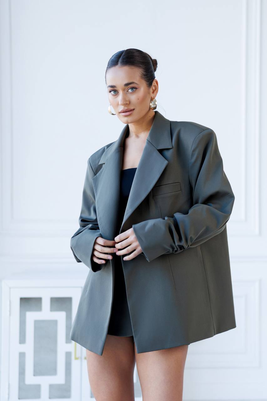 Woman wearing a gray blazer over a black top against a white background