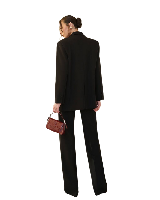 Person wearing a black suit holding a brown handbag on a white background