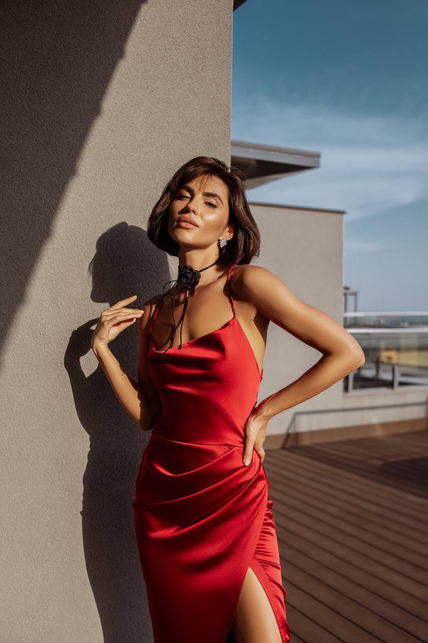 Woman in a red dress standing on a rooftop with a modern building in the background