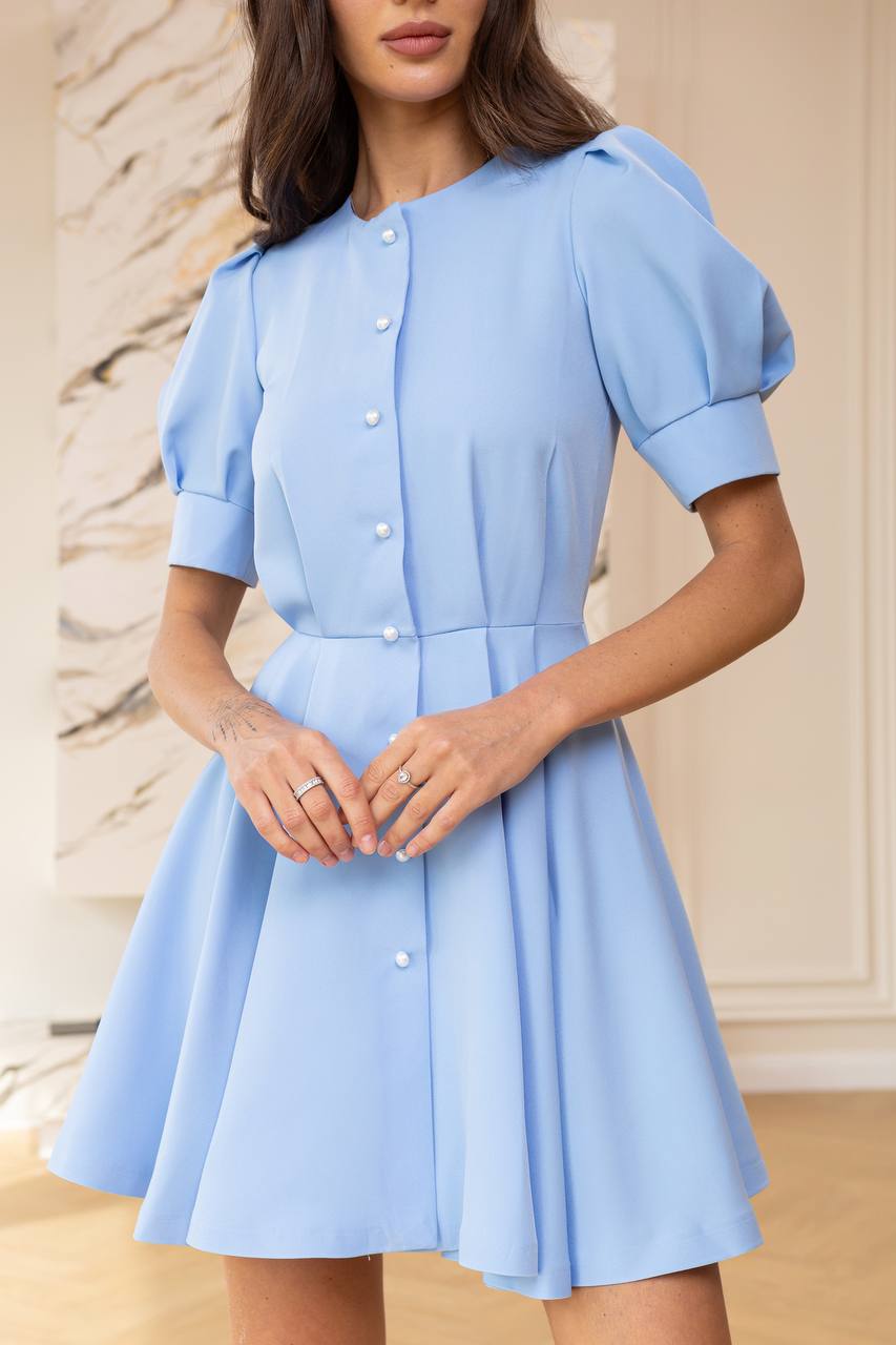 Woman wearing a light blue dress with a neutral background