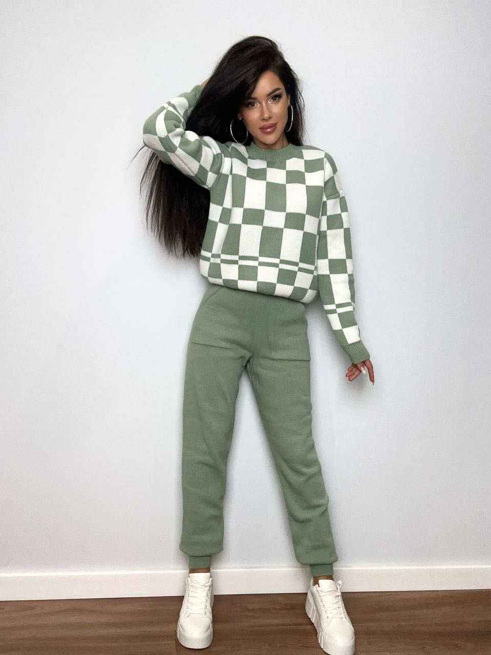 Woman wearing a green and white checkered sweater and matching pants against a plain background