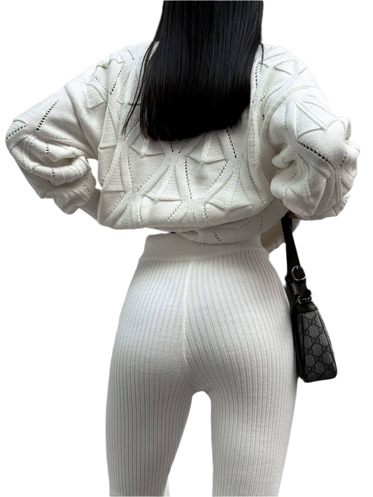 Person wearing a white knit outfit with a black handbag on a white background