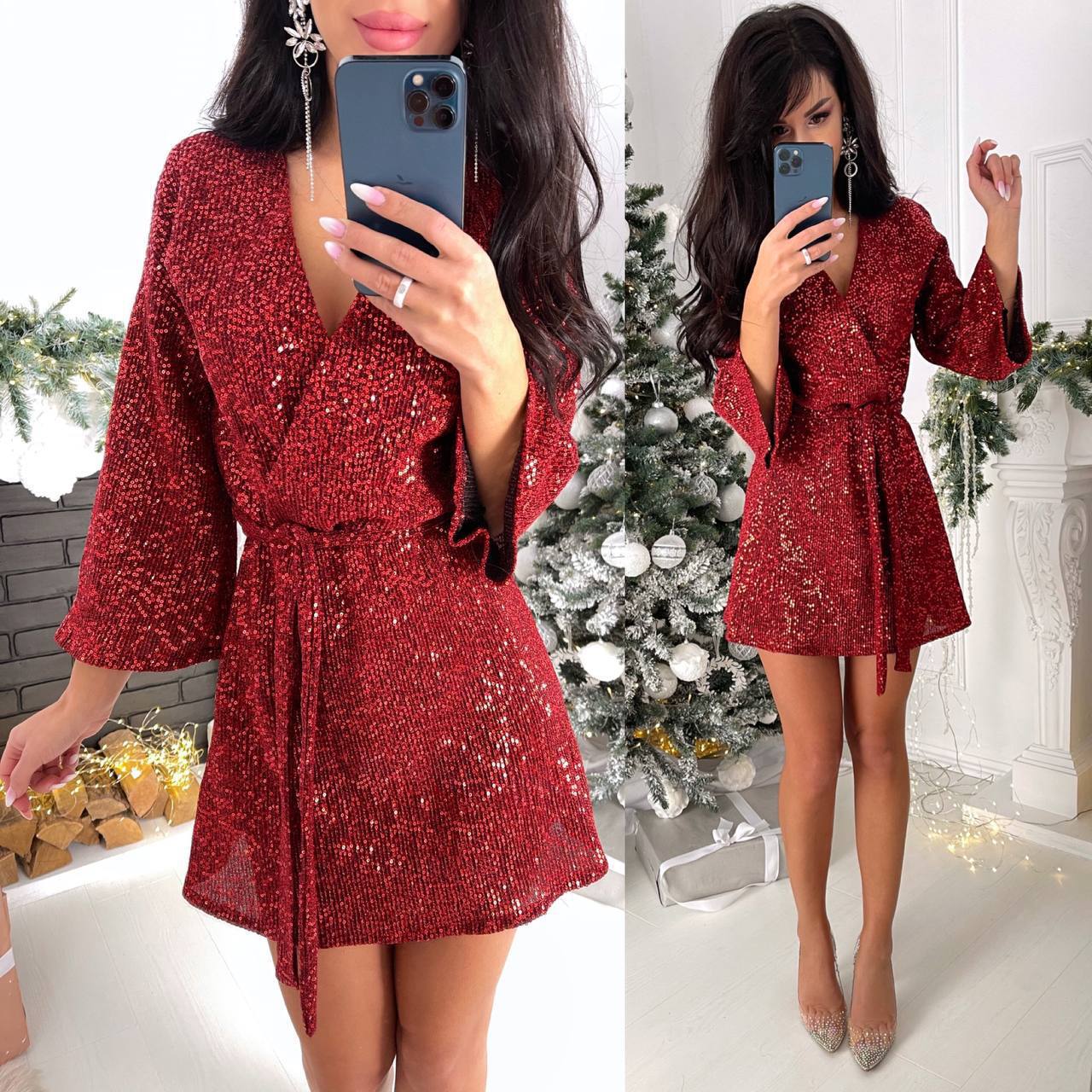 Woman in a red sequin dress taking a mirror selfie in a festive setting with Christmas decorations.